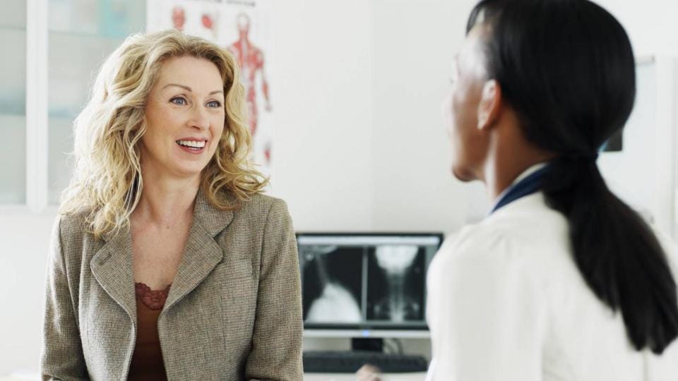 A woman talking to a doctor in a doctor's office.