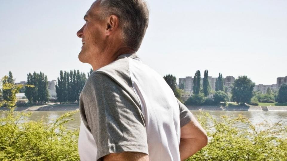 An older man is standing next to a river.