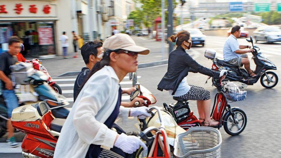 A group of people riding scooters on a city street.