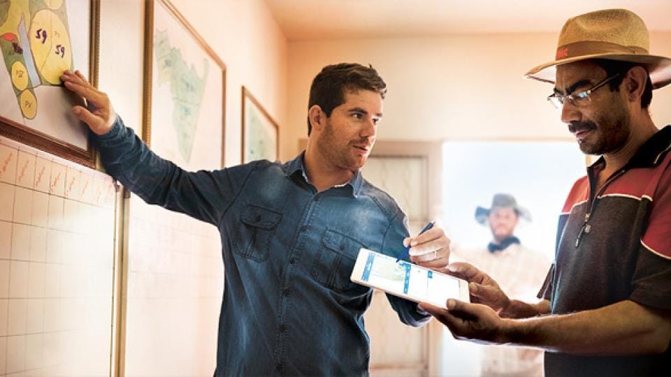 Two men standing in a room looking at a map.