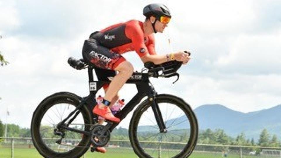 A man riding a bike on a road with mountains in the background.