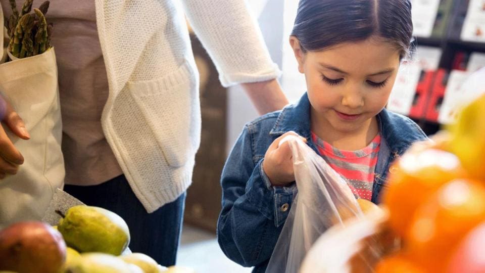 A young girl looking at fruits and vegetables in a grocery store.