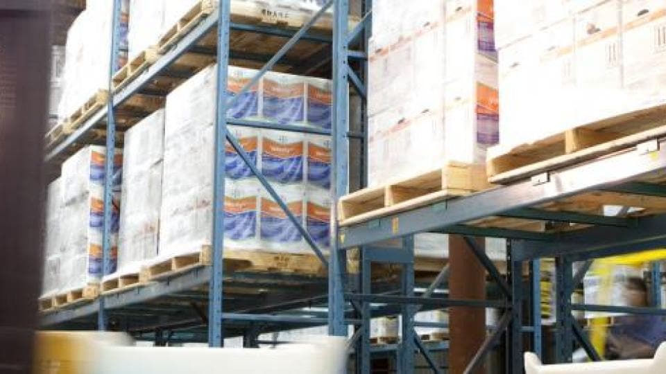 A forklift drives through a warehouse full of pallets.