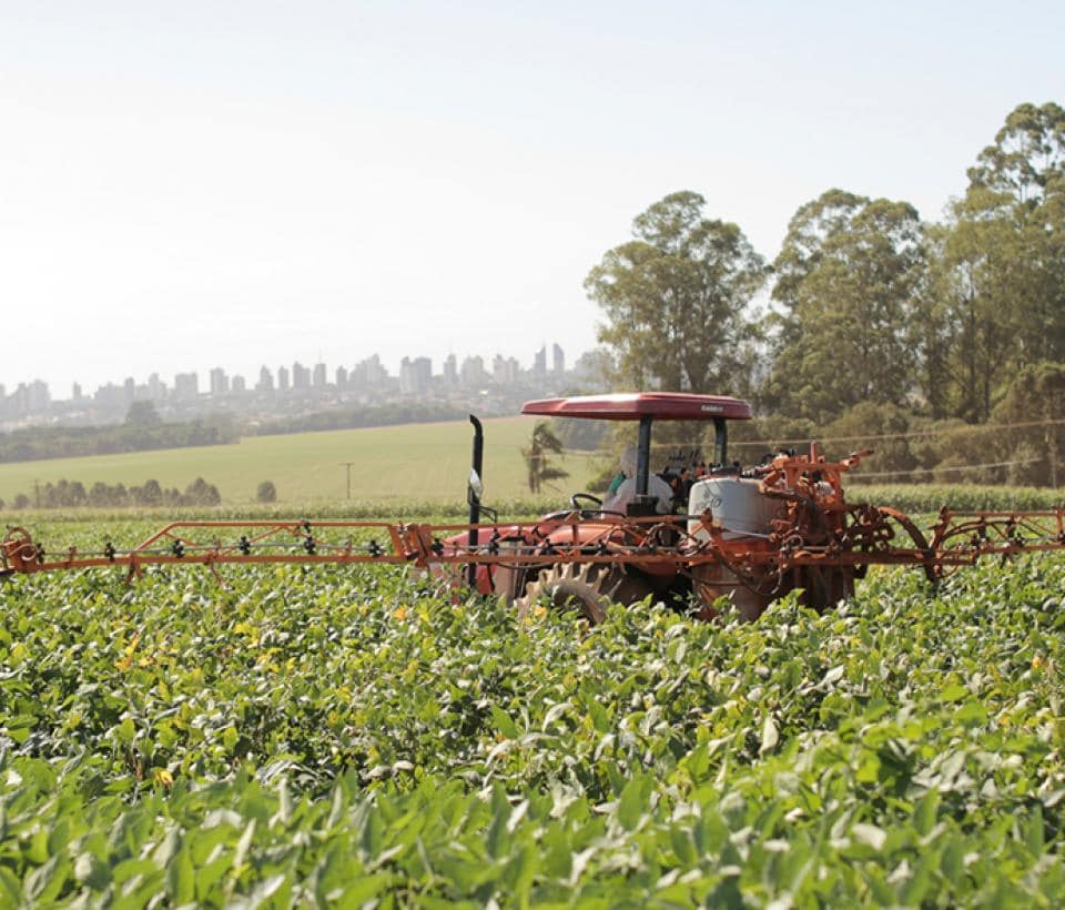 A tractor in a field spraying crops.