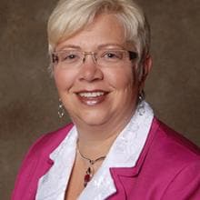 A woman wearing glasses and a pink jacket.