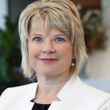 A woman wears a white blazer and a black shirt.