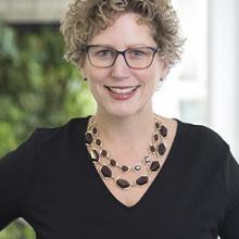 A woman wearing glasses and a black top.