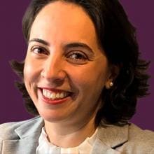 A woman smiles against a purple background.