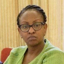 A woman with glasses sits at a table.