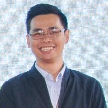 A man wearing glasses and a jacket smiles for the camera.