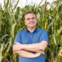 A man stands in a corn field.