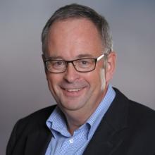 A man wearing glasses and a blue shirt.