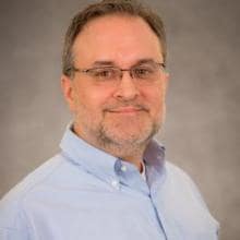 A man wearing glasses and a blue shirt.